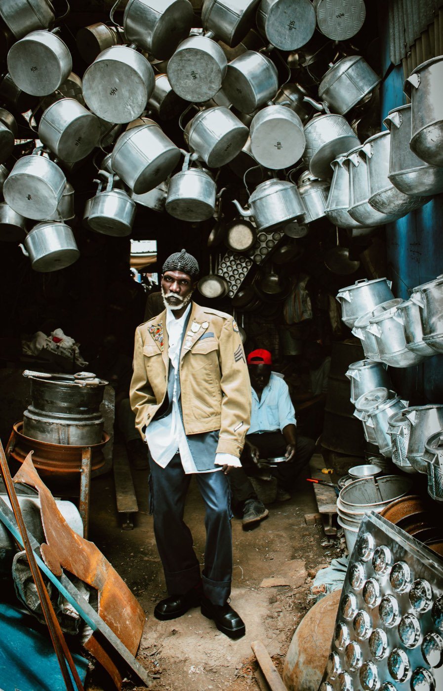 Trader surrounded by metal cookware in a hardware market