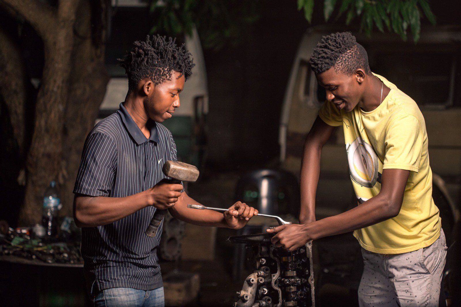 Two mechanics inspecting an engine with hand tools